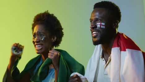 video of joyful african american female and male sport fans with flags of england and portugal