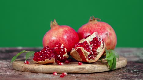 juicy pomegranate with leaves on cutting board rotates slowly.