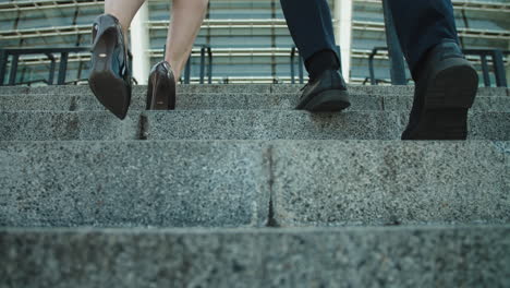 Back-view-of-unrecognizable-business-couple-climbing-up-stairs-outdoors