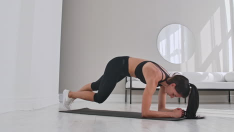 una mujer atlética y hermosa hace plank como parte de su rutina de entrenamiento en el gimnasio.