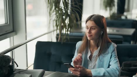 una chica joven agradable escucha música con auriculares en el teléfono