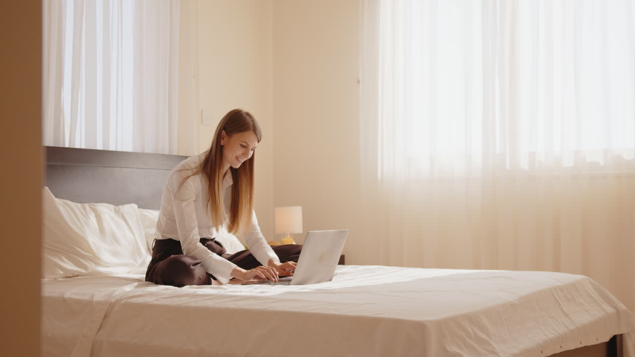 침실에서 노트북으로 일하는 여자