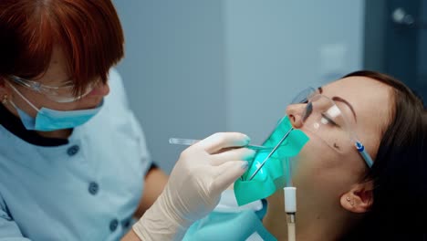 face of a patient in protective glasses in the dental chair. professional stomatologist treating woman's teeth in dental center. stomatology concept.