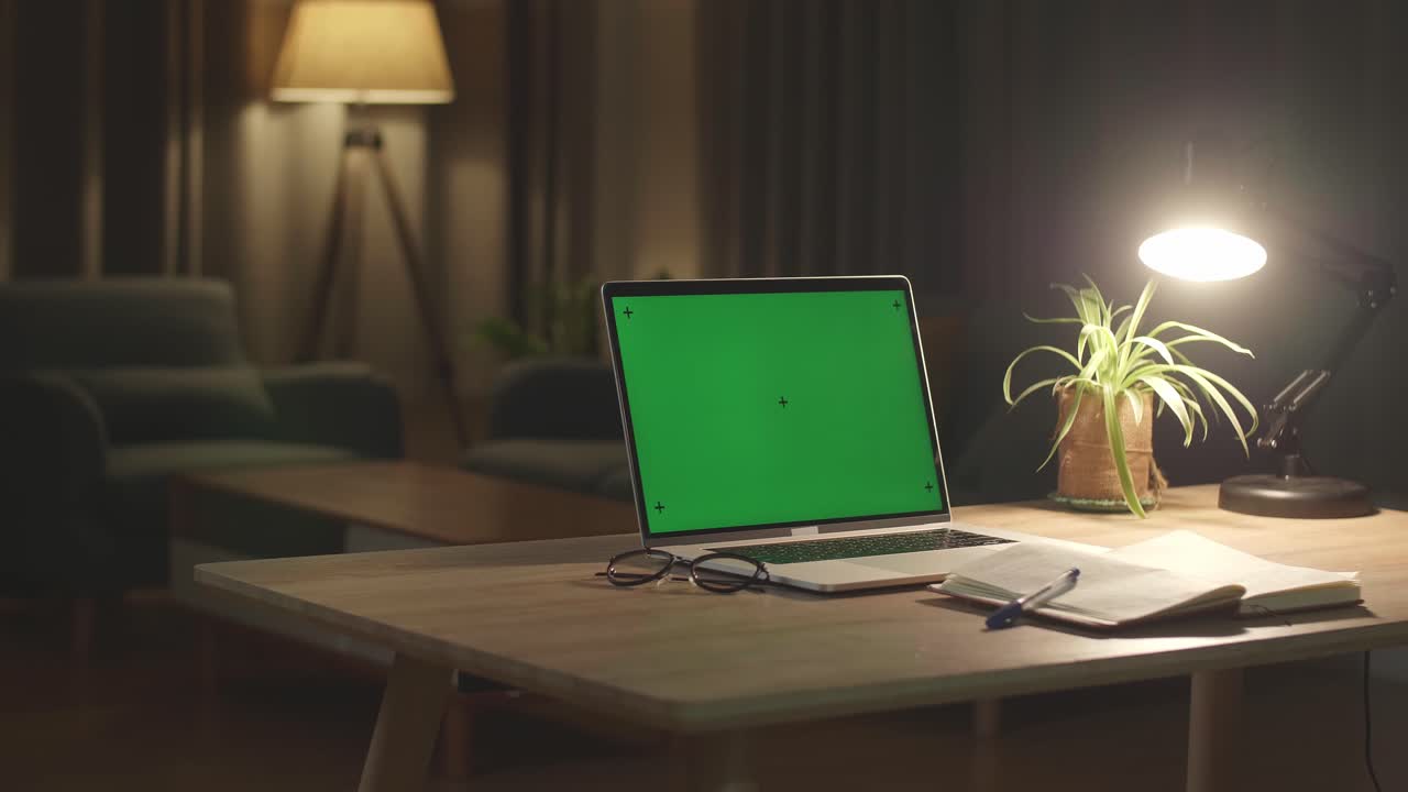 Laptop Computer Showing Green Chroma Key Screen Stands On A Desk In The Living Room. In The Background Cozy Living Room In The Evening With Warm Lights On