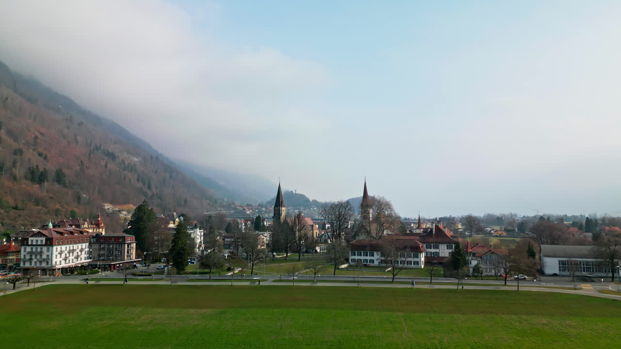 el avión no tripulado se eleva a través de un campo abierto verde a las capillas de interlaken, suiza.
