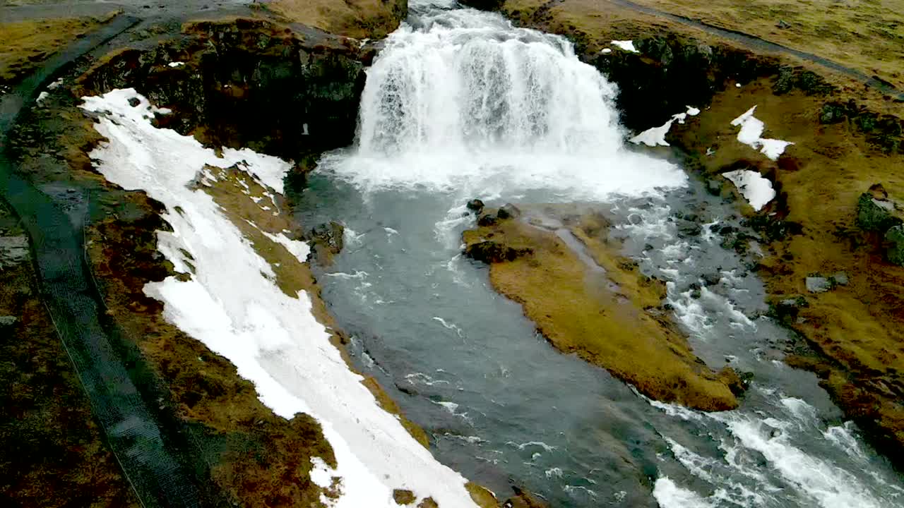 un avión no tripulado de 4k, aéreas, cinematográficas, y tomas de paisajes únicos de una cascada de islandia con nieve se derrite en el lado