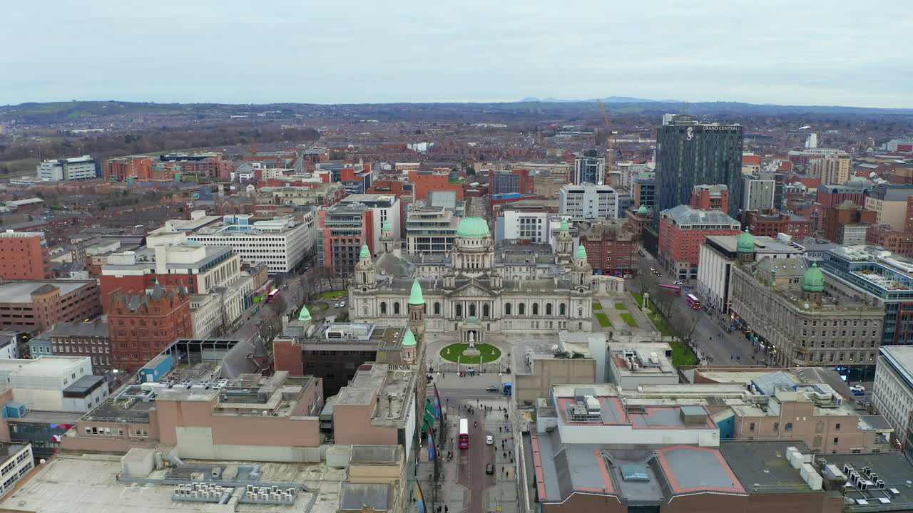 Drone retreating and rising from historic Belfast City Hall to showcase expansive urban landscape
