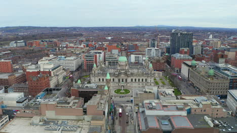 drone retreating and rising from historic belfast city hall to showcase expansive urban landscape