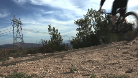 mountain-biker-dropping-off-cliff-in-the-desert-under-power-lines