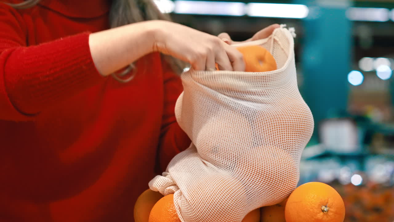 Donna che raccoglie arance in una borsa riutilizzabile in un negozio. Tematiche relative all'ecologia e alla Giornata della Terra