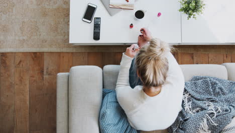 Ein-Blick-Von-Oben-Auf-Eine-Frau,-Die-Zu-Hause-Auf-Dem-Sofa-Liegt-Und-Zehennägel-Malt