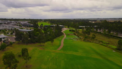 fast drone shot of golf course club house from hole cloudy sky