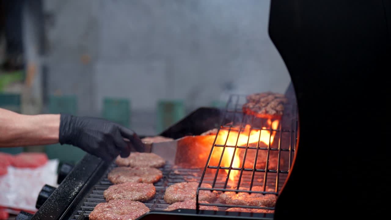 Person Wearing Black Gloves Grilling Beef Burger Patties. Close-up Shot