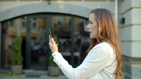 serious business woman having video conference online on smartphone outdoors