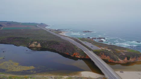 aerial drone view of car driving in fog on pacific coast highway by san gregorio beach in california, usa