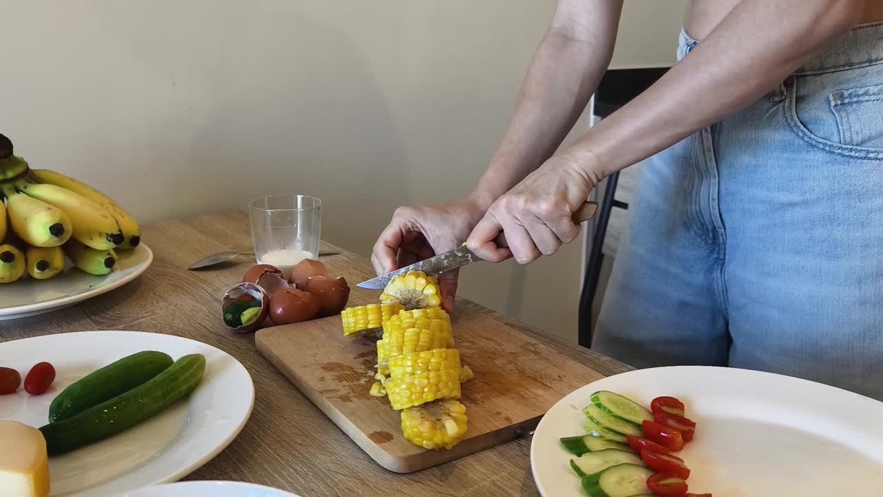 Woman cutting corn in the kitchen
