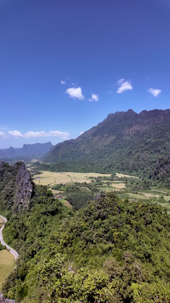 Strada tortuosa tra dolci colline che conduce a uno spettacolare affioramento roccioso con un'ampia valle sottostante e lontane cime calcaree