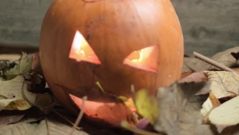 Halloween-carved-pumpkin-as-autumn-leaves-moving-as-breeze-blows-in