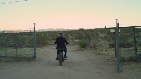 Únase-A-La-Carretera-En-Este-Clip-Cinematográfico-Que-Captura-Cómo-Un-Aventurero-Solitario-Llega-A-Una-Antigua-Y-Encantadora-Granja-En-El-Corazón-Del-Desierto,-Conduciendo-Una-Motocicleta-Tipo-Helicóptero-Antigua.