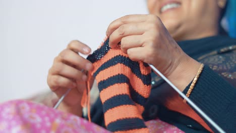 mujer feliz tejiendo una bufanda roja y negra con placer