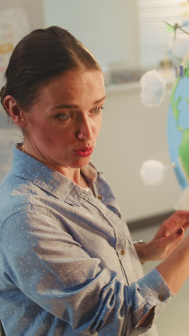 Female School Teacher Educating Science and Renewable Energy Sources Using Model of Planet Earth