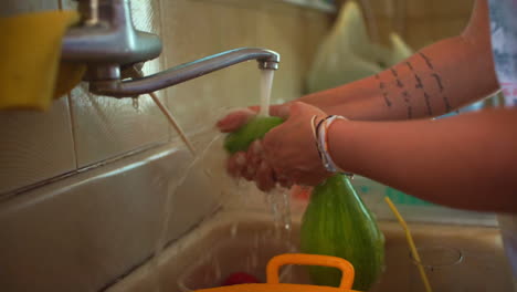 mujer lavando calabaza en el primer plano del grifo de la casa