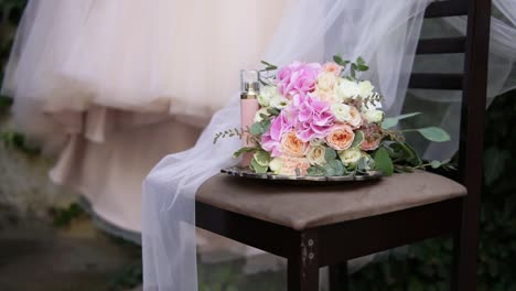 beautiful bridal bouquet on the table with beautiful wedding dress and bridal accessories on the background. wedding dress on shoulders, before ceremony. beautiful wedding bouquet and dress for bride