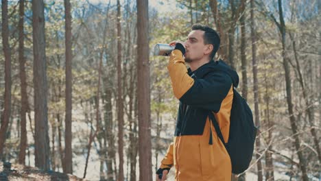 the hiker in the forest drinks water from the bottle 4k