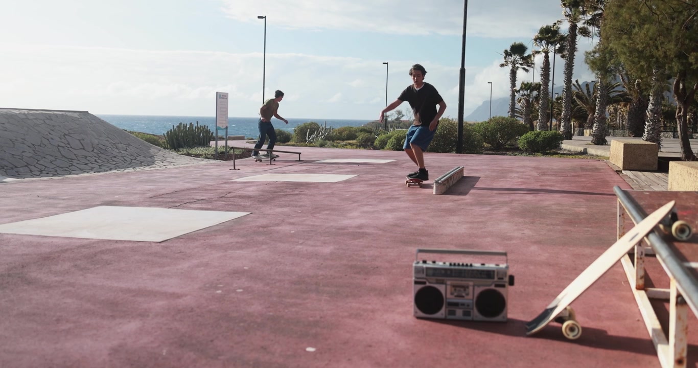 Young Man Skateboarding and Grinding on a Rail at a Coastal Skatepark