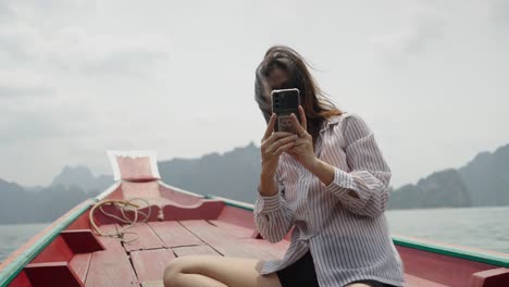 woman using smartphone on a boat in a scenic mountain lake