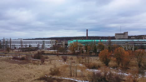 old ruined factory among nature. front view of a large ruined buildings of abandoned plant under gray sky.