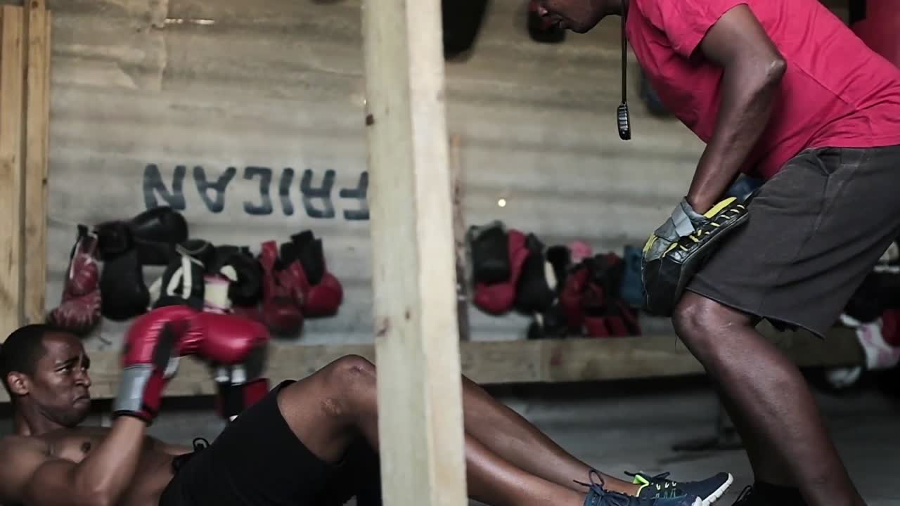 코치 와 권투 선수 가 체육관 에서 권투 를 연습 하고 있다