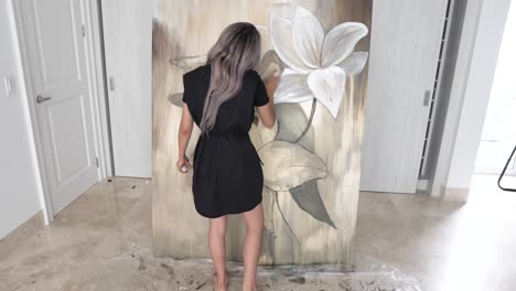 beautiful female artist standing and working on painting in back static view