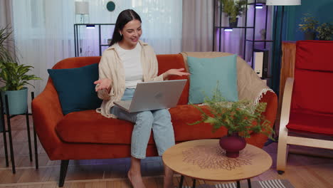 Woman-sitting-on-home-couch,-looking-at-camera,-making-video-conference-call-with-friends-or-family