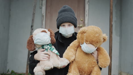 a child in a mask keeps his toys on which masks are worn. on the doorstep of your house. depression and quarantine