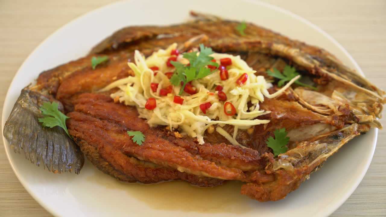 lubina frita con salsa de pescado y ensalada picante en el plato