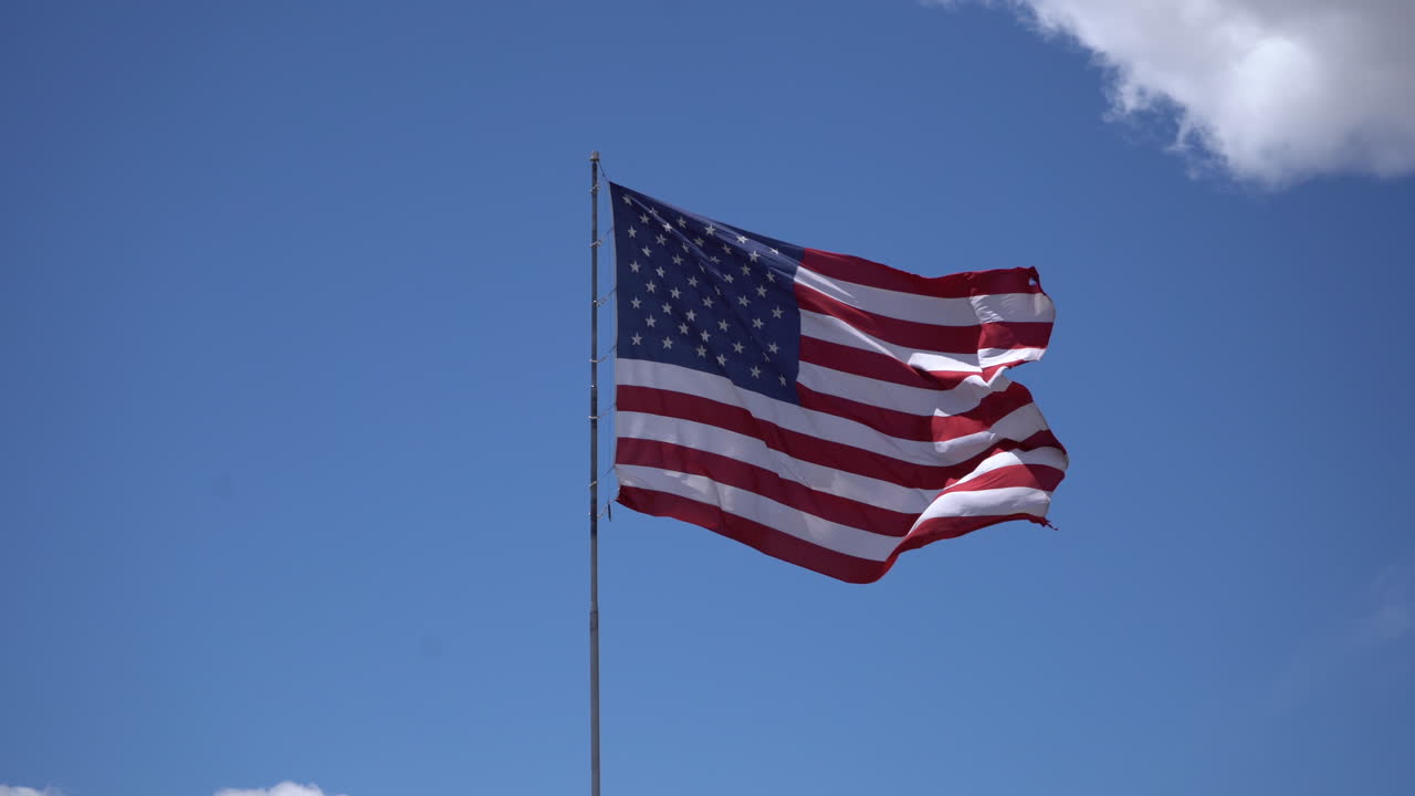 Bandeira americana a agitar-se no céu azul com nuvens