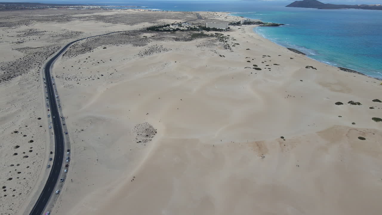 corralejo beach fuerteventura 위에서 상승하는 공중 풍경 비어있는 곡선 도로가 모래 해변을 가로질러 해안선을 향해 휘어집니다.