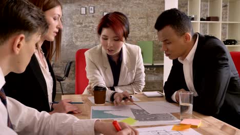 business team of mixed ethnicity holding meeting in modern office building, asian woman talking and discussing project