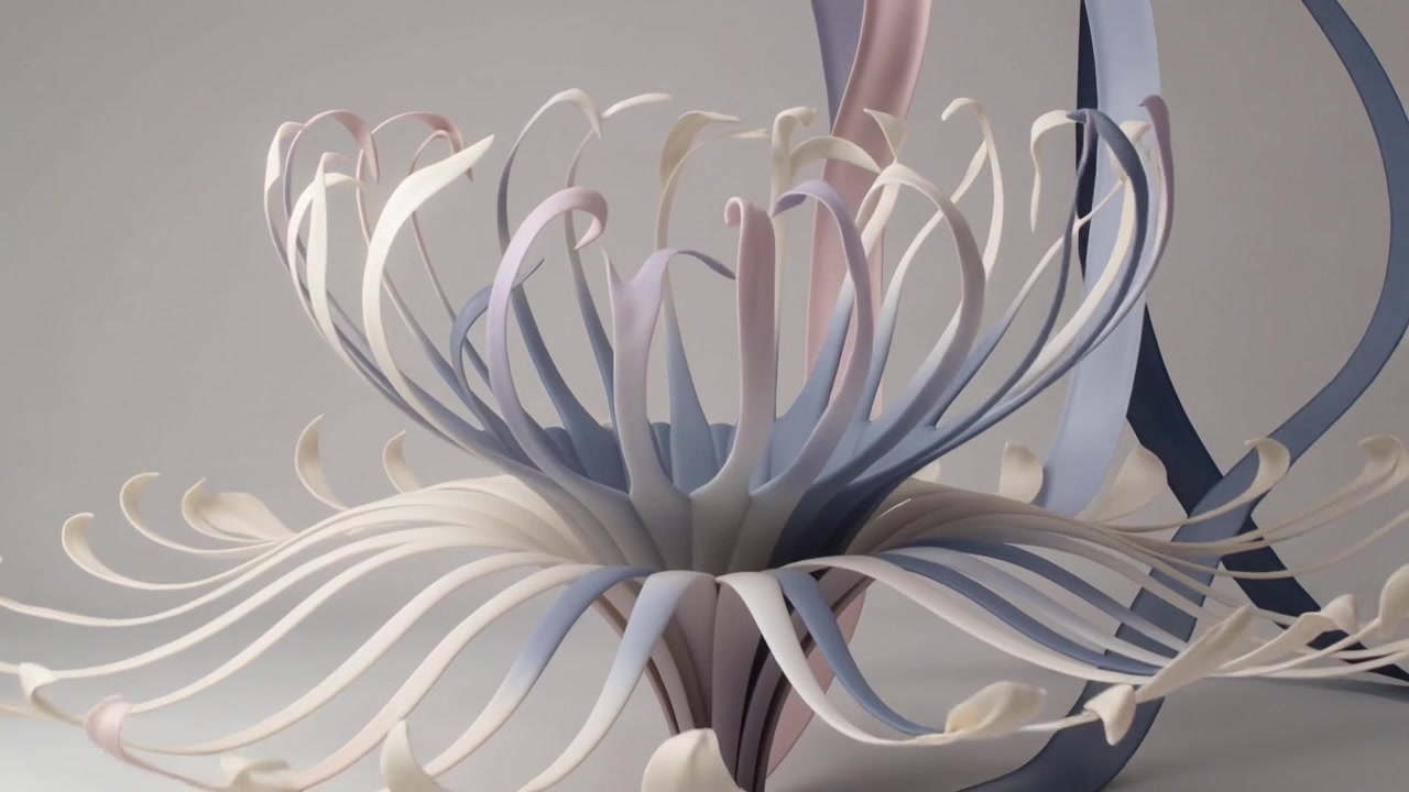 Unfurling ribbon flower sculpture over frames on pale tabletop, revealing trailing ribbons and stem