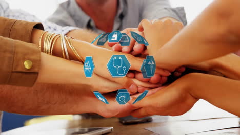 animation of globe with medical icons over diverse business people stacking hands