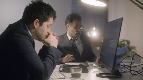 Two-businessmen-working-together-in-office-late