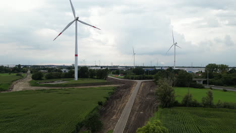 Wind-energy-farm-near-busy-highway-and-city-in-Belgium,-aerial-view