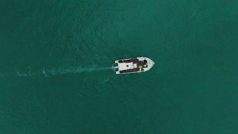 Top-down-aerial-view-of-motorboat-navigating-through-the-turquoise-mediterranean-ocean,-scientists-on-global-warming-expedition