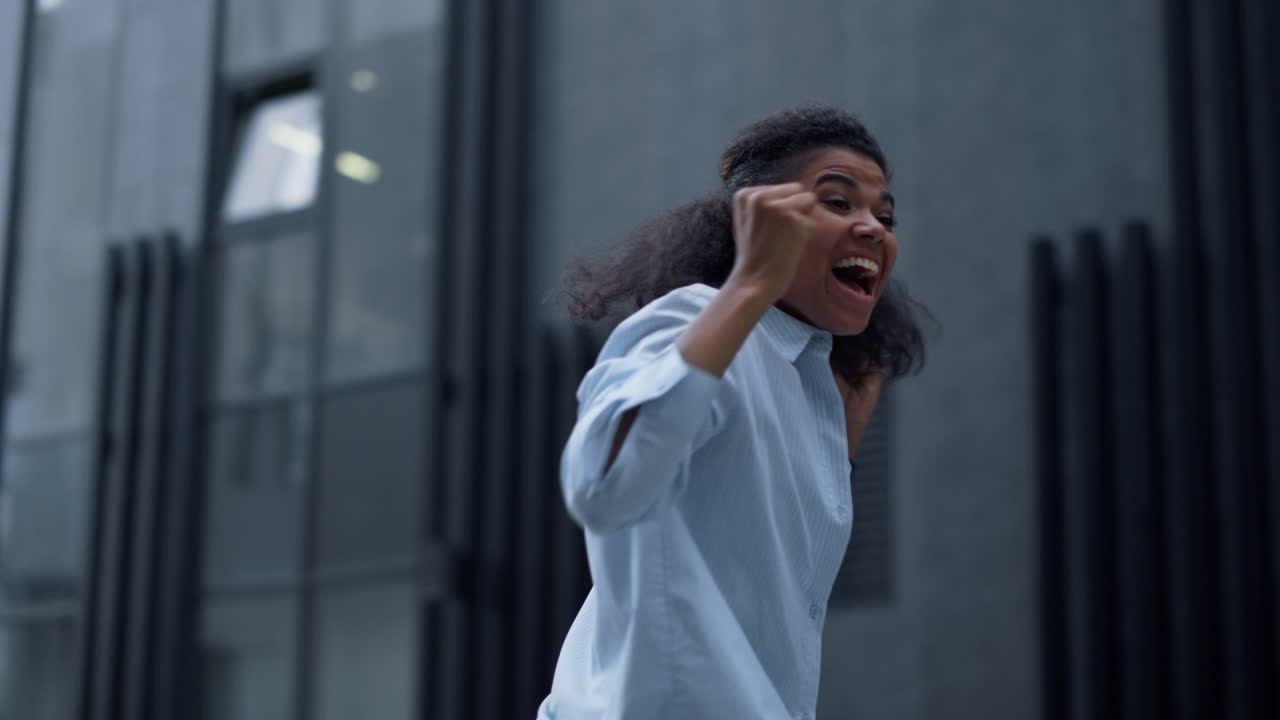 Happy woman celebrating success at office building alone. Overjoyed student jump