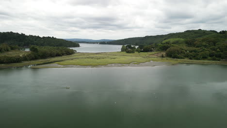 dolly downward aerial of a large twisting river lush green trees with canoe