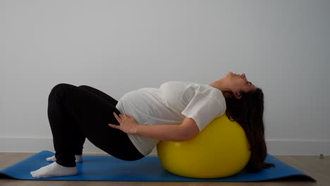 pregnant woman doing pilates over a fitball at home