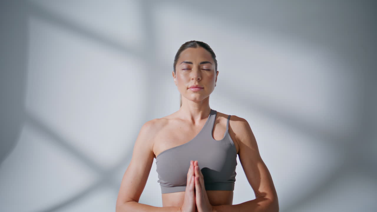 Mulher fazendo a asana Namastê em uma videochamada matinal. Mulher meditando olhando para a câmera