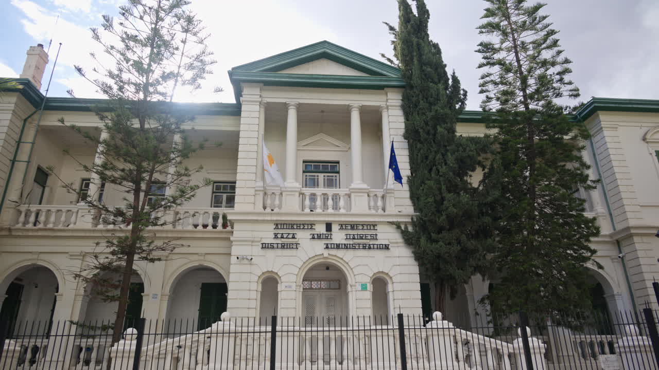 Limassol, Kypros – 26. helmikuuta 2026: Etunäkymä Limassolin piirihallintorakennuksesta, uusklassisesta rakennuksesta, jossa on pylväitä, parvekkeita ja lippuja.