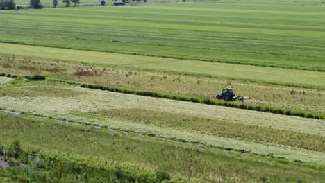 Lonely-tractor-working-in-endless-green-vibrant-farmland-field,-aerial-orbit-view